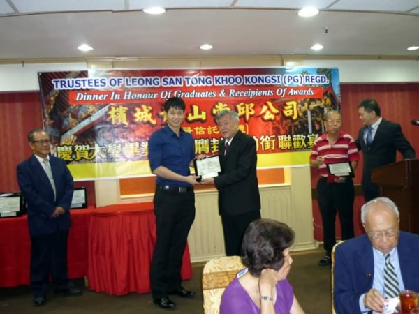 Khoo Kay Hock presenting a plaque to a Khoo Graduate.