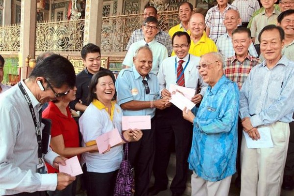 Charitable act: Khoo (blue long-sleeved shirt) presenting cheques to 12 welfare organisations at Leong San Tong Khoo Kongsi.